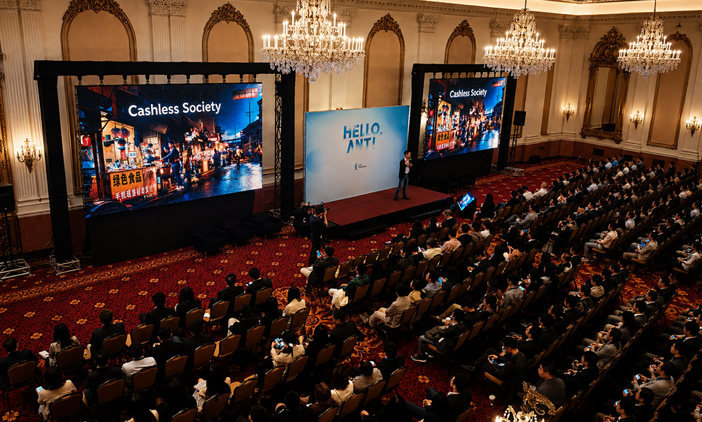 Presenter addressing a conference audience between two large projection screens