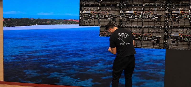 DAV Production technician installing modular LED wall panels displaying an ocean scene