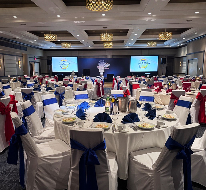 Banquet room with dual projection screens prepared for the 2025 CAHON Oncology Forum