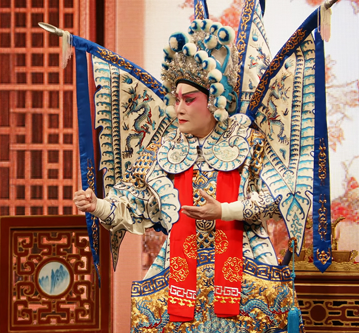 Cantonese opera performer in an elaborate blue, white, and red costume onstage
